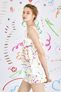 Stylish woman wearing a playful Knitting Silk Camisole Top with vibrant, colorful patterns on a whimsical background.