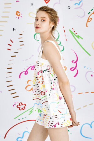Stylish woman wearing a playful Knitting Silk Camisole Top with vibrant, colorful patterns on a whimsical background.
