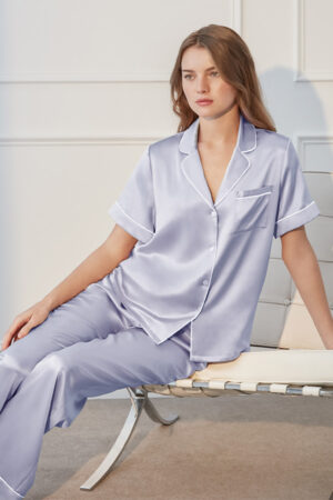 Model in lilac MANITO Authentic Short Sleeve Pajama Set seated on a chair, showcasing silky shine and relaxed fit.