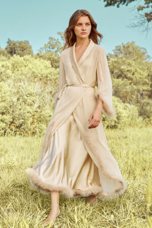 Woman wearing Diva Feather Trimmed Long Robe in silk georgette with hand-stitched feather trim, walking outdoors.