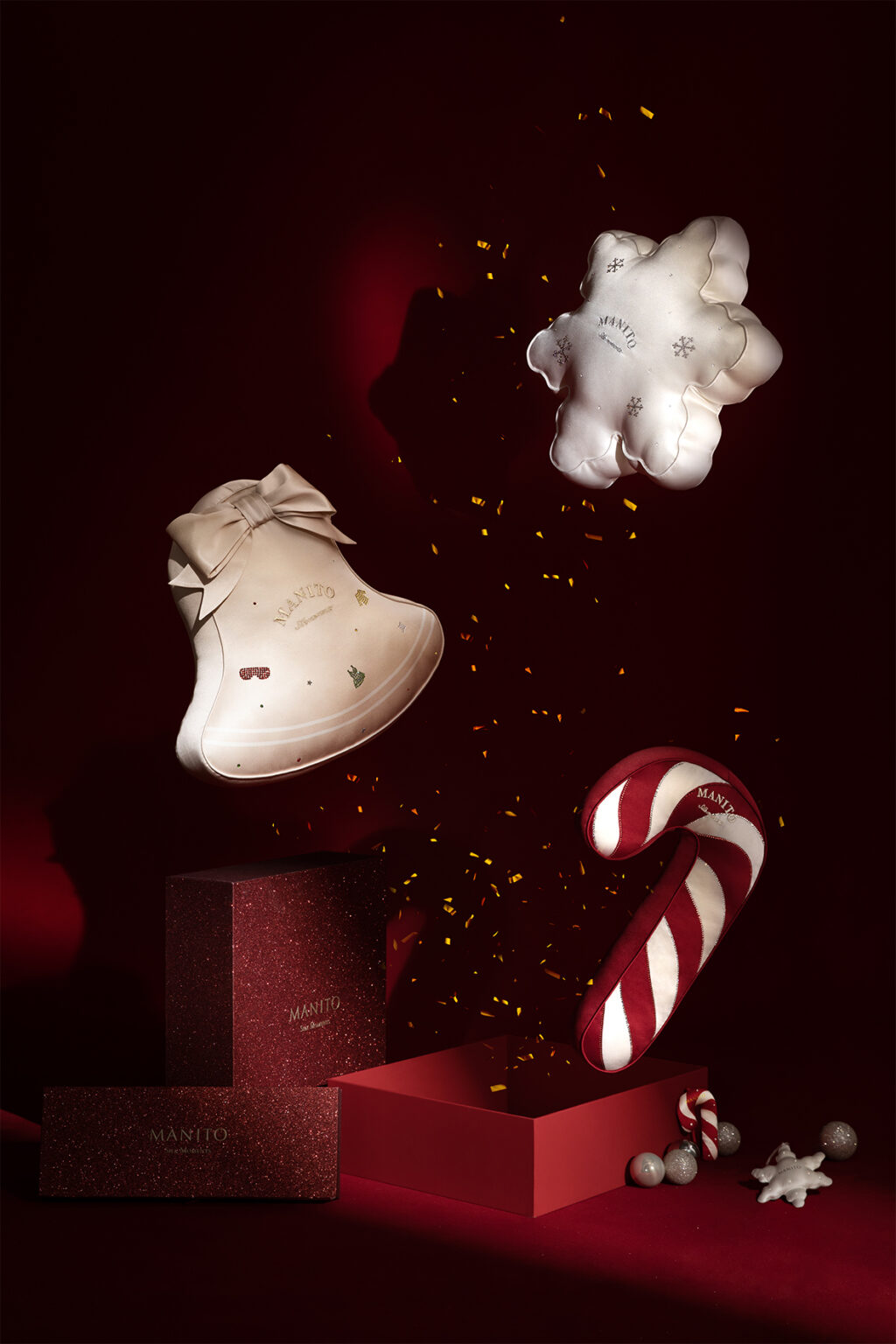 MANITO's luxurious silk cushions designed for Christmas, featuring a bell, candy cane, and snowflake, set against a rich festive backdrop.