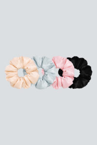 Set of soft silk scrunchies in pastel pink, sky blue, and classic black on a neutral background