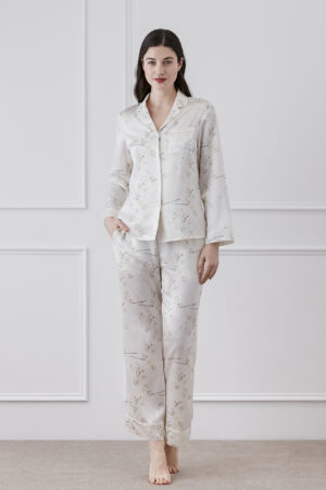 Woman displaying Princess Louise silky pajama set with delicate floral print, posing in a interior.
