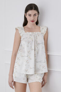 A woman in Princess Louise short pajama set with frilled sleeves, standing in the white background.