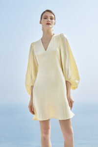 Elegant woman in a Pure V-neck Lantern Sleeve Silk Mini Dress against a serene blue sky backdrop.