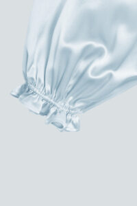 Close-up of blouse sleeves cuffs, featuring ruffle trim design and lantern sleeves style.