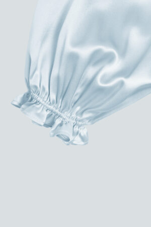 Close-up of blouse sleeves cuffs, featuring ruffle trim design and lantern sleeves style.