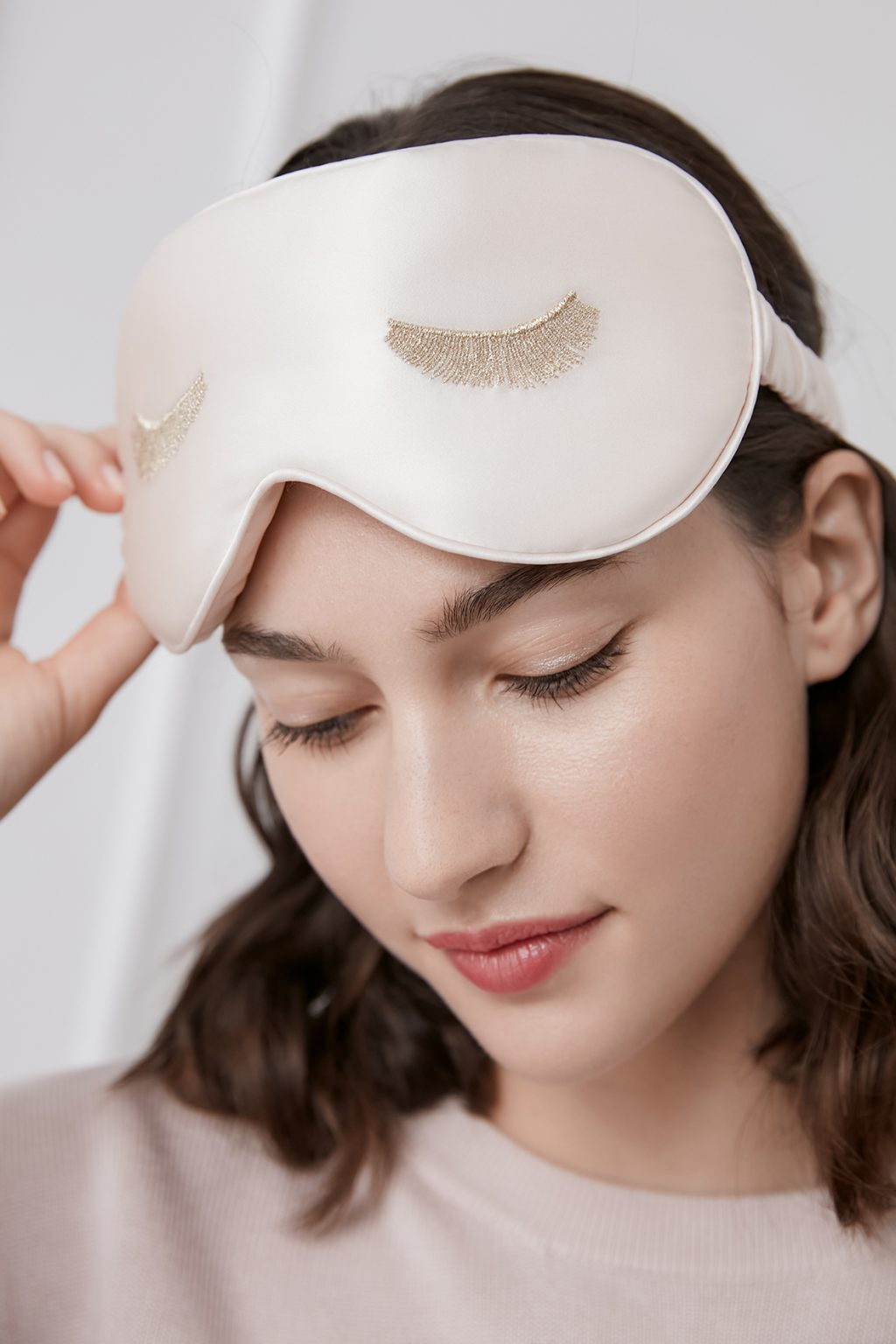 Woman wearing the pink Lash Contour Silk Eye Mask, showcasing its silky texture and the gentle protection for daily comfort.