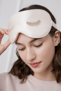 Woman wearing the pink Lash Contour Silk Eye Mask, showcasing its silky texture and the gentle protection for daily comfort.