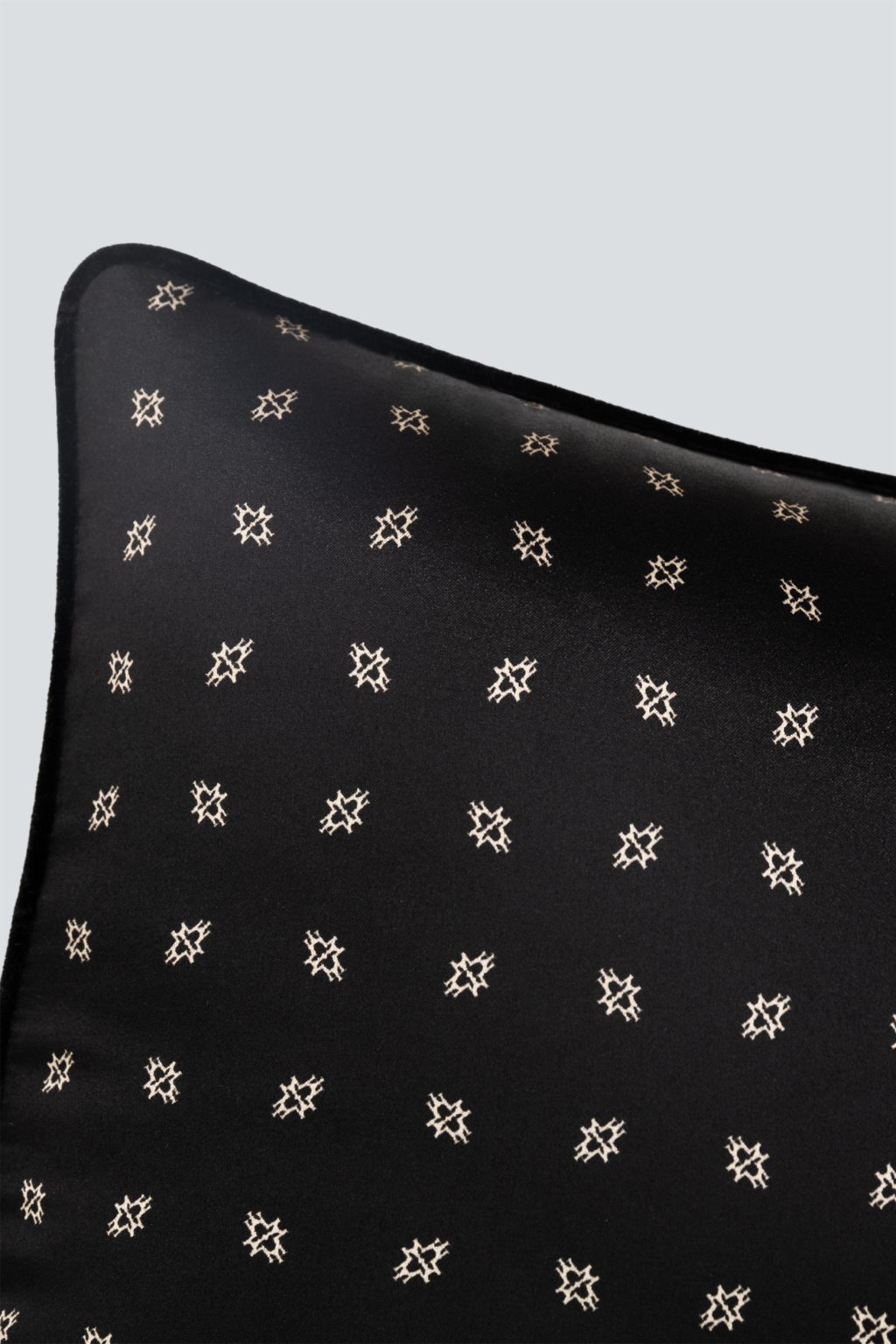 Signature MT Silk Lumbar Pillow displaying an elegant black silk fabric adorned with a subtle golden motif for refined back support.