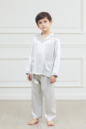 Young boy in an elegant blue silk pajama set with a sharp collar and pocket detail.