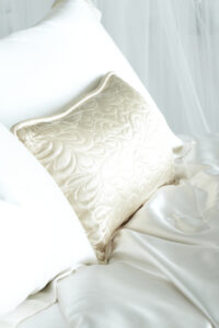 A single quilted silk pillow on smooth satin bedding, reflecting elegance and luxury.
