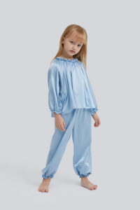 Pensive little girl in a Fairy silk loungewear set with a blue top and matching pants.