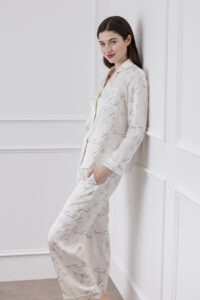 Side profile of a smiling woman modeling a Princess Louise silky pajama set with intricate floral prints.