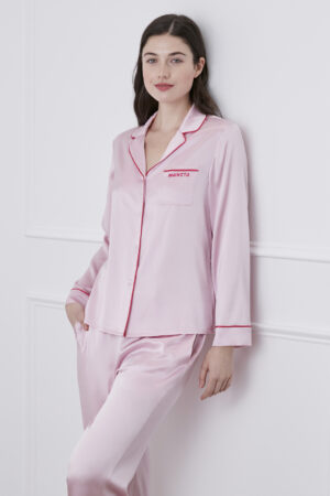 Woman wearing Macaron Silk Pajama Set with pink trim and MANITO logo, offering elegant sleepwear comfort.