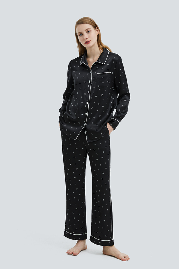 Woman wearing the Signature Women's Pajama Set in a chic black with contrasting white piping and playful print.