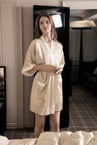 Woman standing in a luxury interior wearing Whisper Women's Short Silk Kimono with relaxed fit and elegant design.