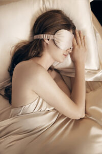 Model resting with a MANITO silk eye mask from the Eye Mask Renewal Subscription for gentle, comfortable sleep.