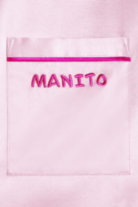 Close-up of the Manito logo embroidered on the pocket of a pink Macaron Silk Pajama Set.