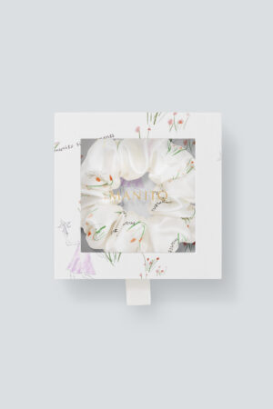 Close-up view of the Princess Louise Silk Scrunchie packaging featuring a floral design scrunchie visible through a clear package.