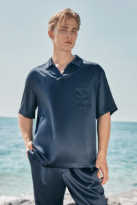 A man in the navy version of the MANITO Remington Men's Short Sleeve Pajama Set poses confidently with hands in pockets.