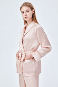 The elegant woman wearing the Elite Silk Robe has her hands in pockets and a belt around her waist for added design.