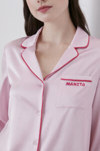 Woman wearing Macaron Silk Pajama Set with elegant piping details and MANITO branding