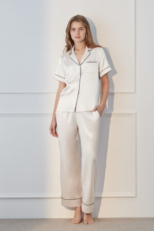 Model in ivory MANITO Authentic Short Sleeve Pajama Set with black trim, showcasing timeless elegance.