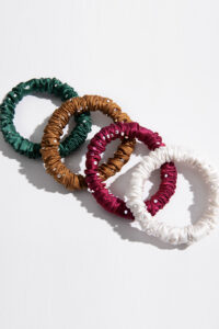 Colorful MANITO Twinkle Mulberry Silk Scrunchies in green, gold, red, and white with crystal details.