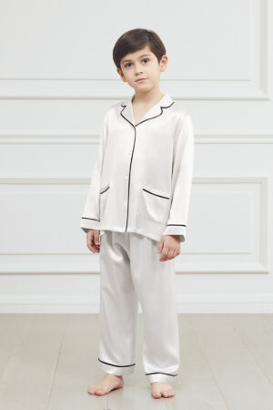 Little boy in soft blue authentic silk pajama set, standing with a smile on his face.
