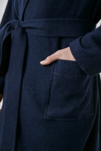 Model adjusting MANITO Bomber Men's Knit Robe, highlighting button and front pocket craftsmanship.