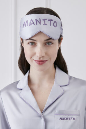 Close-up of a woman wearing a lavender Macaron Silk Eye Mask by MANITO, complemented by her silk pajama top.