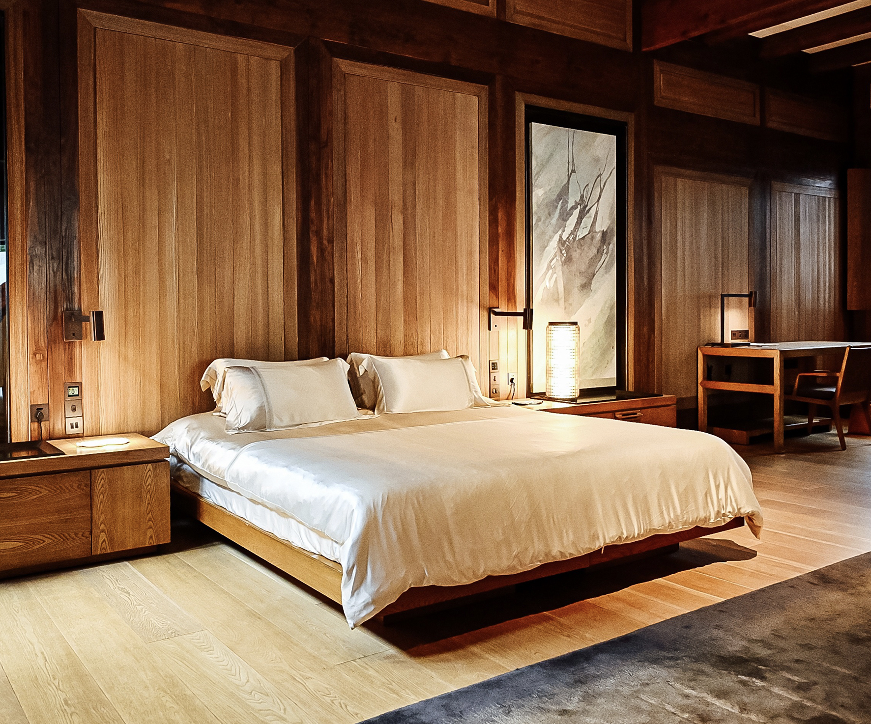 A luxurious bedroom featuring MANITO silk bedding set on a minimalist wooden bed frame, with soft lighting and elegant decor enhancing the serene atmosphere.