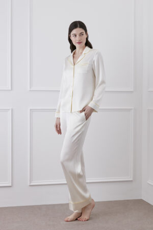 Woman showcasing the Macaron Silk Pajama Set with elegant piping details.