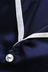 Detail close-up of navy Coco Lady Pajama Set with ivory trim and shimmering silk texture.