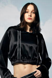 Woman in a front pose with a Sportif Silk Tracksuit featuring hood down and branded trim.