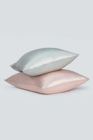 A duo-tone silk pillowcase set with one pillow in a lustrous silver and the other in soft pink, presenting an image of elegant comfort.