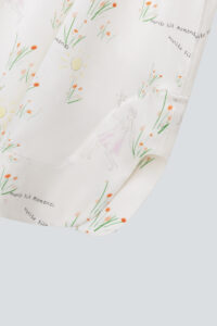 Close-up of the hem of Princess Louise silk slip dress featuring whimsical illustrations and 'manito' text.