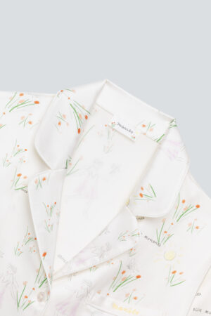 Elegant collar detail of a silky pajama set with the 'mamito' logo and soft floral sketches.