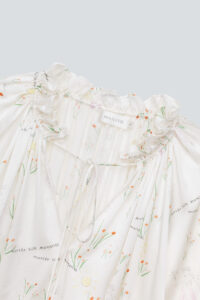 Intimate glimpse of the ruffled neckline and MANITO branding on a Princess Louise Silk Nightgown.