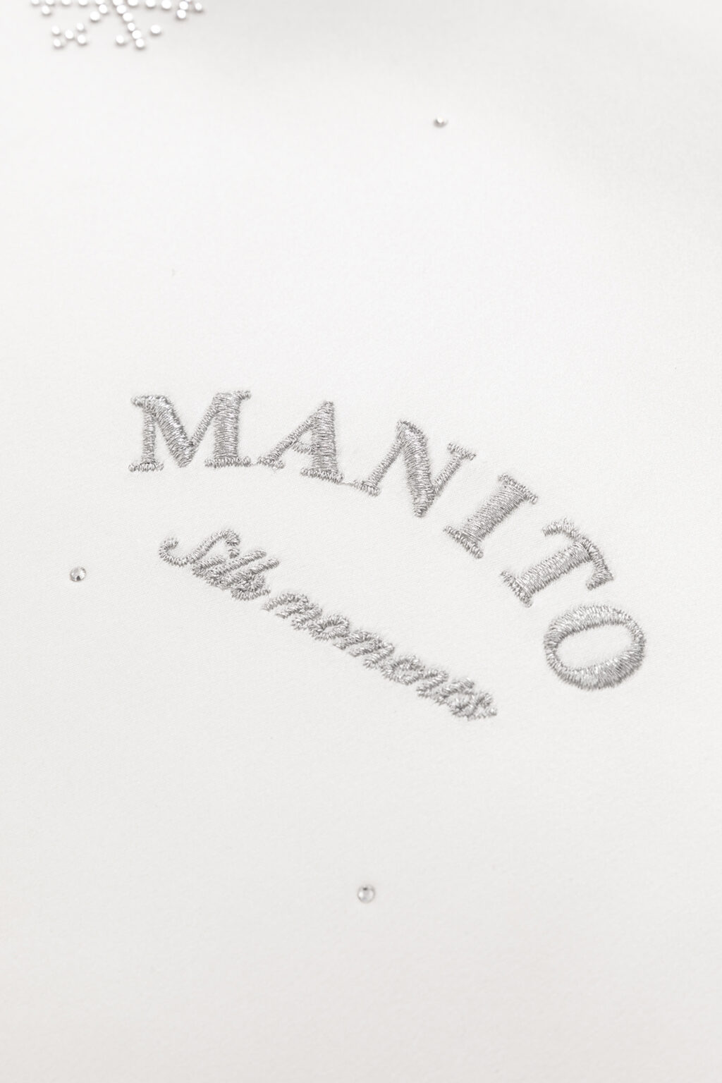 Close-up of MANITO's signature monogram, 'Silk Moments', representing the brand's dedication to bespoke silk elegance.