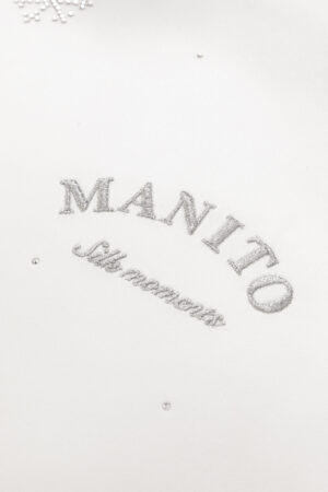 Close-up of MANITO's signature monogram, 'Silk Moments', representing the brand's dedication to bespoke silk elegance.