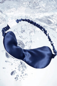 MANITO HA Silk Eye Mask in navy gently drifts through water, evoking a cool, hydrating sleep experience.