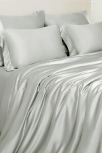Aether silk bedding in quartz gray charmeuse silk, showing soft draping fabric and modern urban elegance.