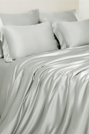 Aether silk bedding in quartz gray charmeuse silk, showing soft draping fabric and modern urban elegance.