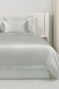 Aether silk bedding is displayed on a modern bed, highlighting its quartz gray sheen and minimalist elegance.