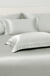 Aether silk bedding and matching pillowcases in quartz gray charmeuse silk, accented with subtle plaid trim.