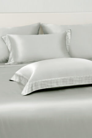 Aether silk bedding and matching pillowcases in quartz gray charmeuse silk, accented with subtle plaid trim.