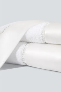 Aqua Bath Towels layered with silk trims and lace logo, crafted from natural Sea Island cotton for fluffy softness.