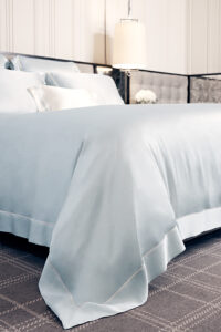 Detail view of MANITO Authentic Silk Duvet Cover in baby blue color showcasing the elegant border trim and natural drape.